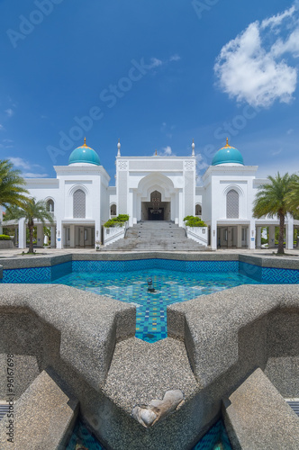 The vertical of Mosque Albukhary located in Alor Star, state of Kedah, Malaysia with its fountain and squares in the foreground and blue sky with clouds in the background.