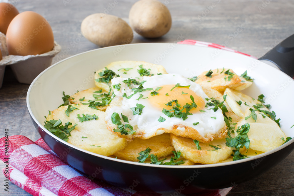 Potatoes, fried eggs and parsley in a frying pan Potatoes, fried eggs and parsley in a frying pan