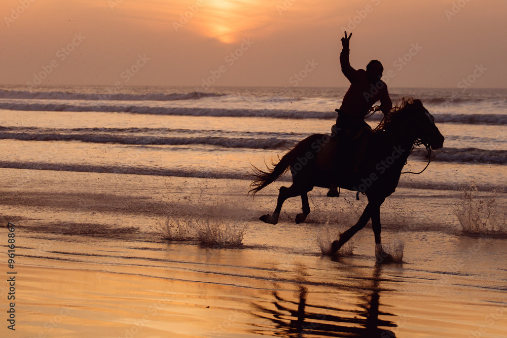 Silhouette of a horse and rider galloping on beach at sunset. Stock ...