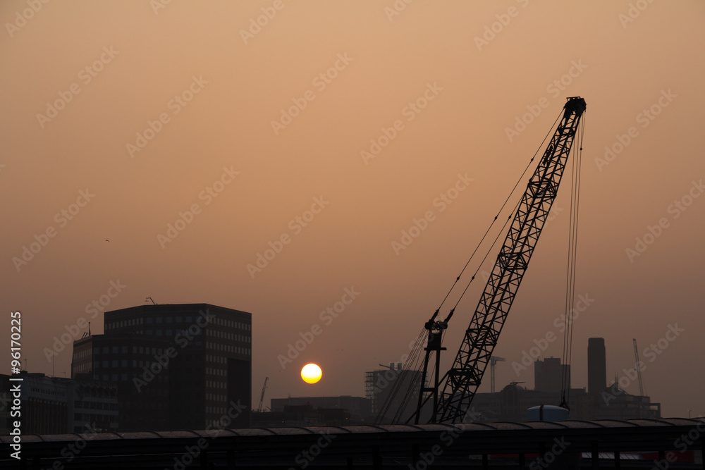 Evening city skyline with a crane working long into the night during construction works Evening city skyline with a crane working long into the night during construction works