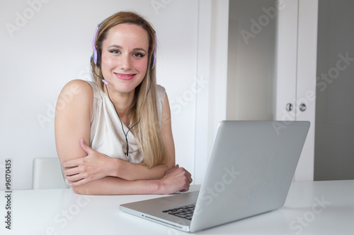 Attractive smiling blonde woman with headset and laptop posing for the camera.