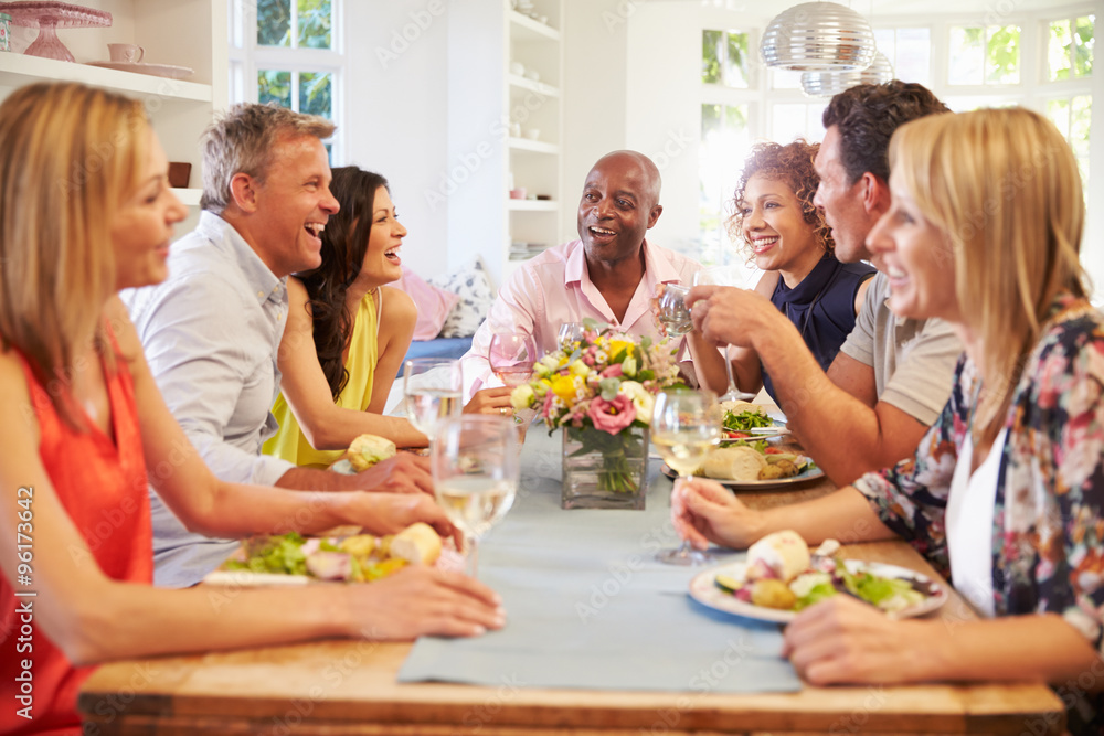 Mature Friends Sitting Around Table At Dinner Party