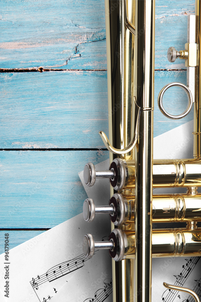 Naklejka premium Trumpet with sheet music on blue wooden boards