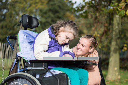 Disabled girl in a wheelchair relaxing outside / Disabled girl in a wheelchair relaxing outside with a care assistant