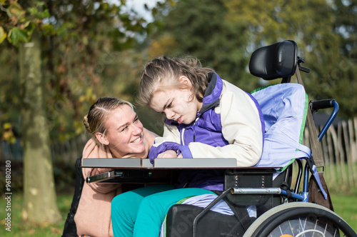 Disabled girl in a wheelchair relaxing outside / Disabled  girl in a wheelchair relaxing outside together with a care assistant