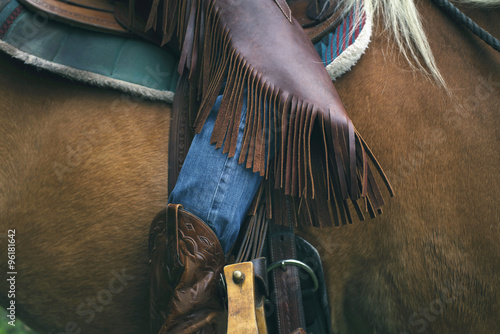 Close-up of western style horse chaps while sitting on horse.