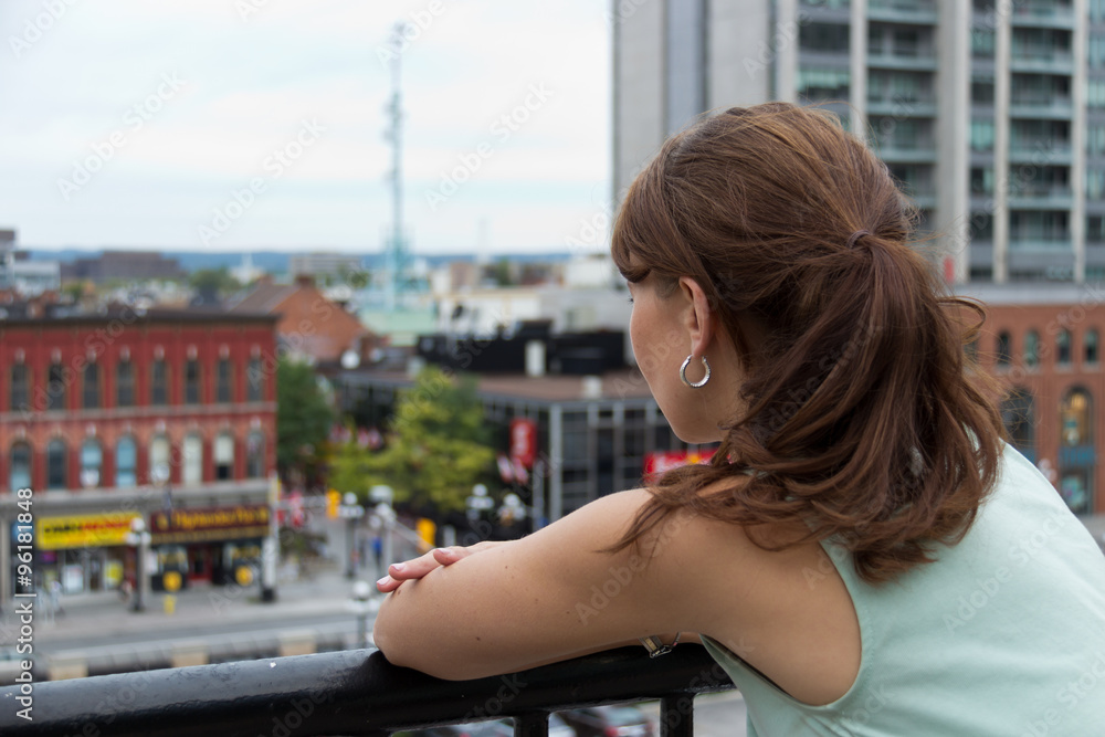Woman looks out to city from balcony