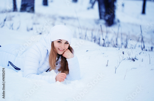 Happy girl lying on the snow in winter