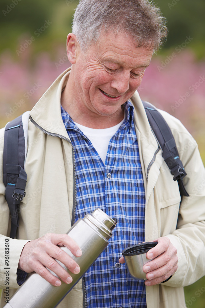 Senior Man Pouring Hot Drink From Flask On Walk Senior Man Pouring Hot Drink From Flask On Walk