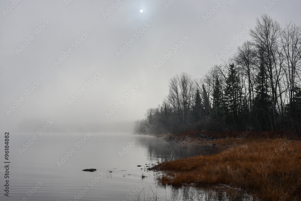Dense fog envelopes Ottawa River and shoreline - obscured sunshine through fog, bright diffusion, mid-morning sunrise.