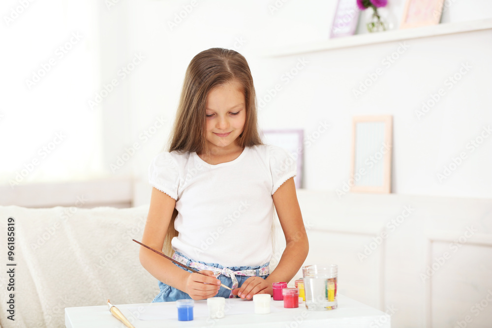 Cute little girl painting picture on home interior background Cute little girl painting picture on home interior background
