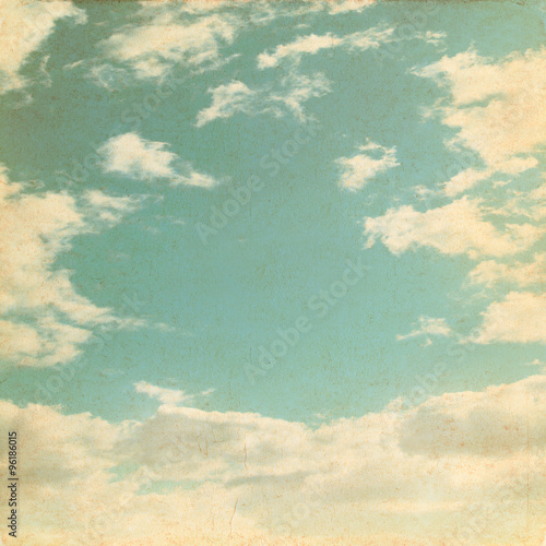 Old paper background with blue sky and white clouds in grunge style. 