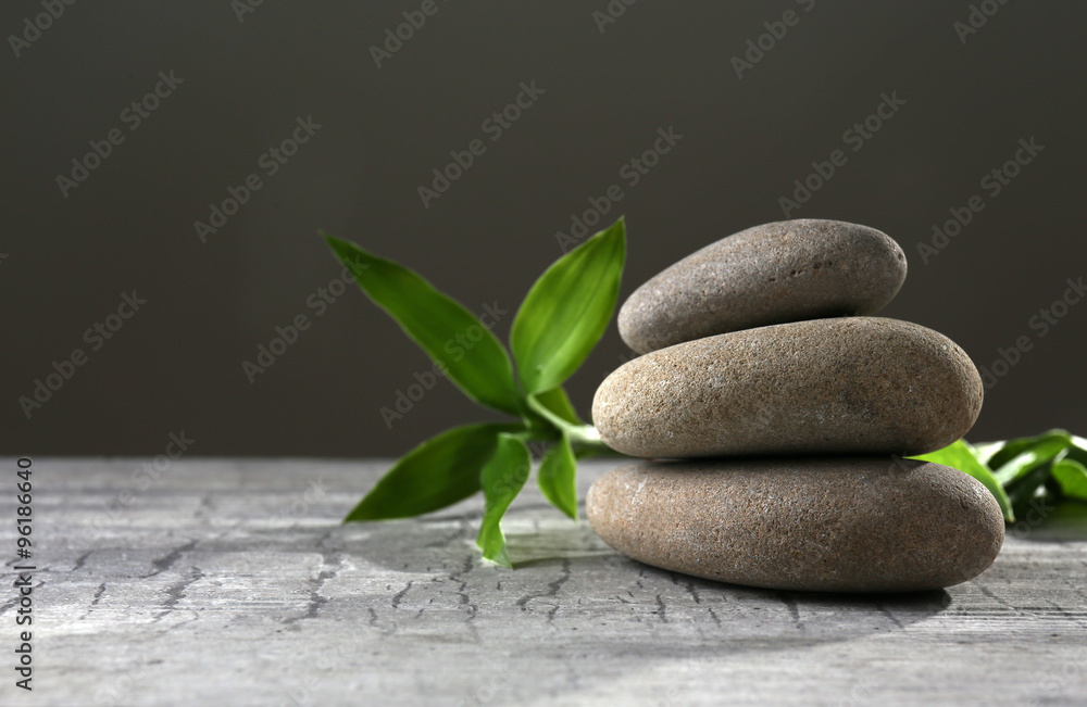 Black spa stones and green flowers, on dark grey background Black spa stones and green flowers, on dark grey background