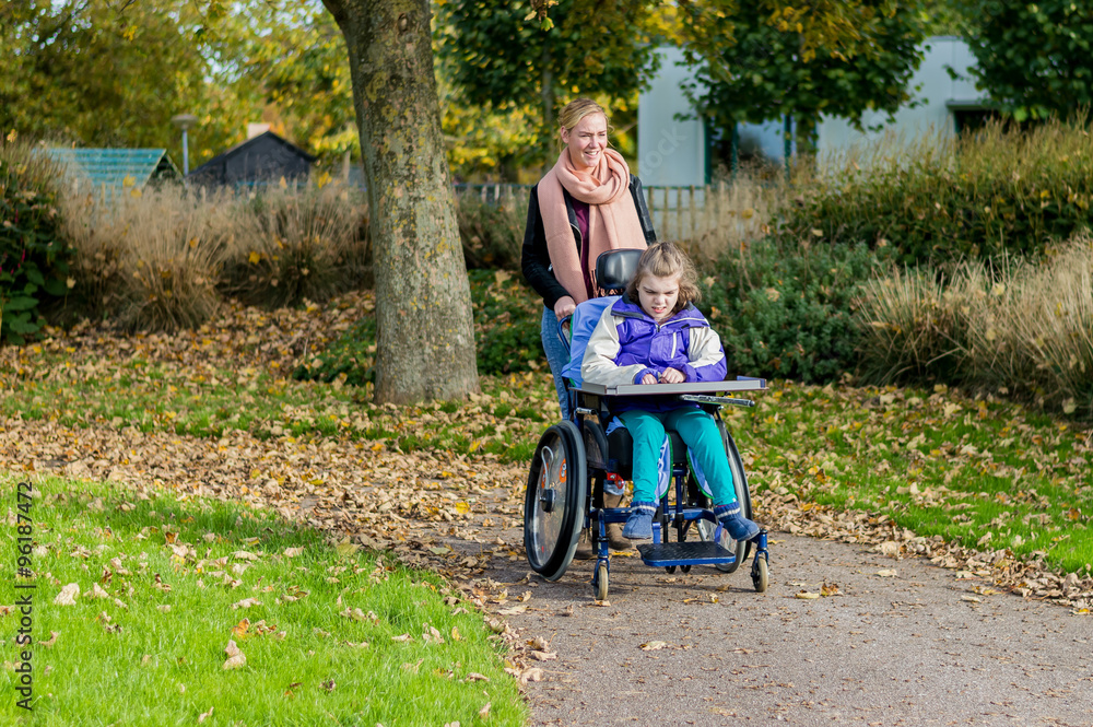Disabled girl in a wheelchair relaxing outdoors / Disabled girl in a wheelchair relaxing outdoors together with a care assistant Disabled girl in a wheelchair relaxing outdoors / Disabled girl in a wheelchair relaxing outdoors together with a care assistant