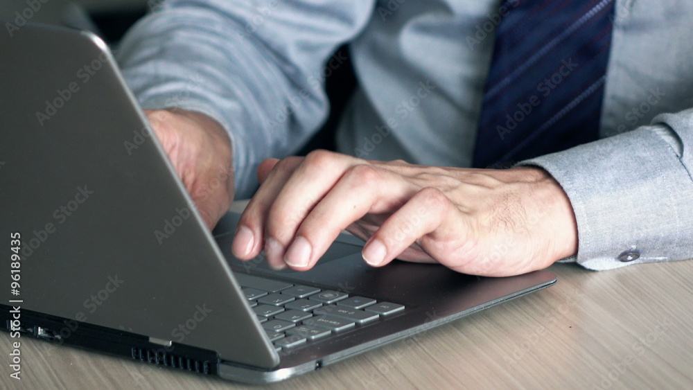 Businessman hands typing on modern laptop by table
Businessman hands typing on modern laptop by table