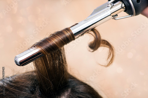 Tablou pe pânză Hairstylist using a curling iron or tongs