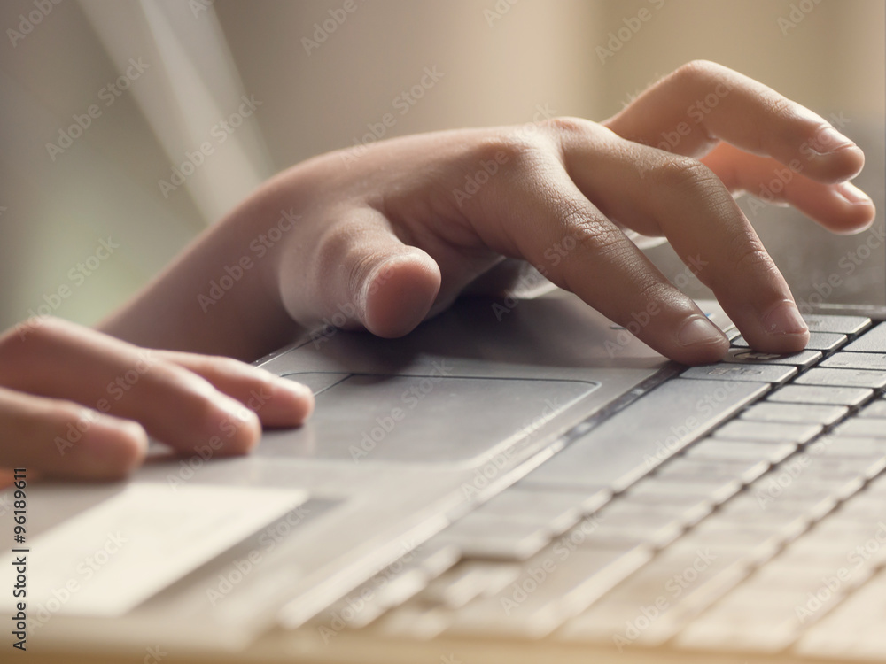 asian kid is typing on a laptop by his hand. asian kid is typing on a laptop by his hand.