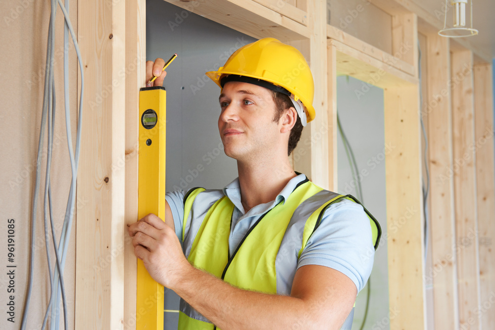 Builder Checking Work With Spirit Level Builder Checking Work With Spirit Level