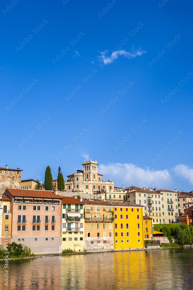 facade of historic houses in Bassano del Grappa, Italy with reflection in river brenta