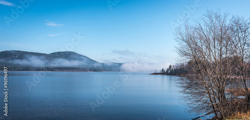 Panoramic view of fog lifting off the Ottawa River in the morning, blue sky, clear bright day with Laurentian hills.