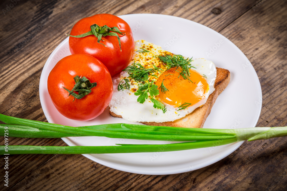 Fried egg on toast with greens and tomato Fried egg on toast with greens and tomato