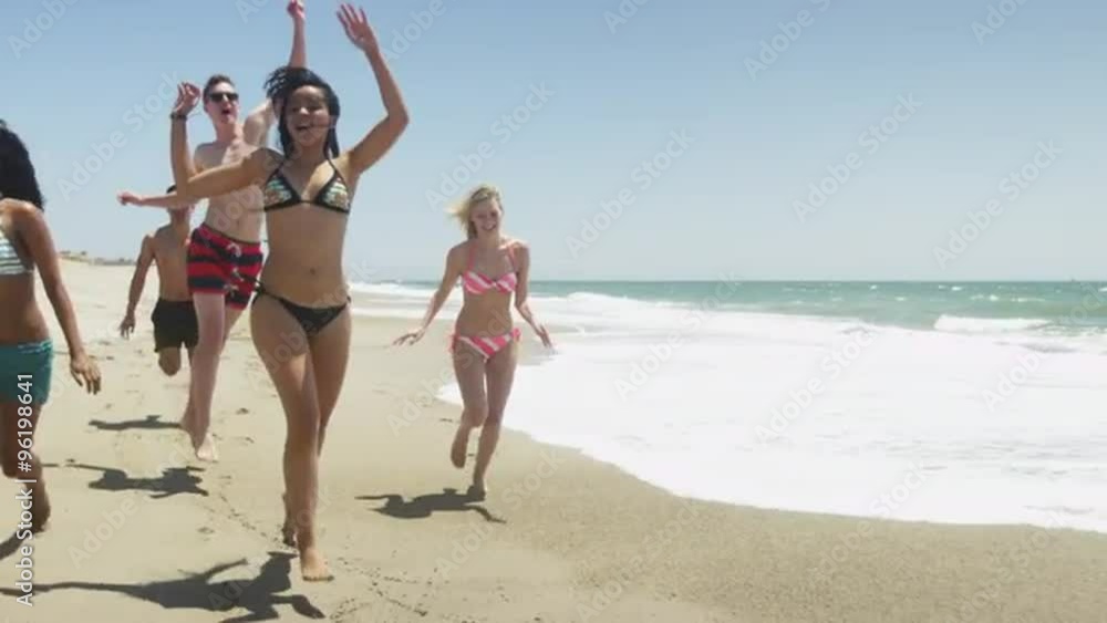 Young interracial healthy adults running on beach in slow motion Young interracial healthy adults running on beach in slow motion