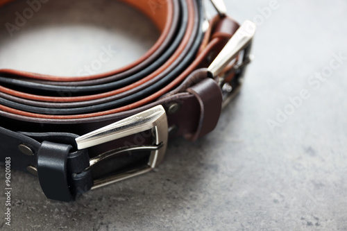 Leather belts with buckles on gray background