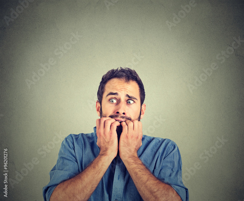 Portrait anxious young man biting his nails fingers freaking out
