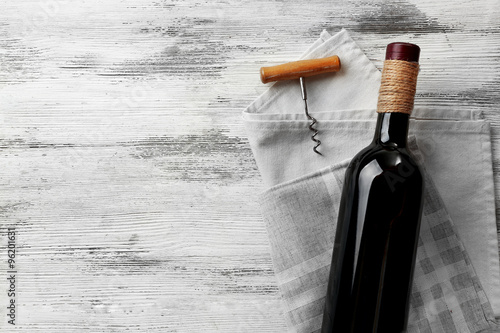 Wine with corkscrew on a light wooden background