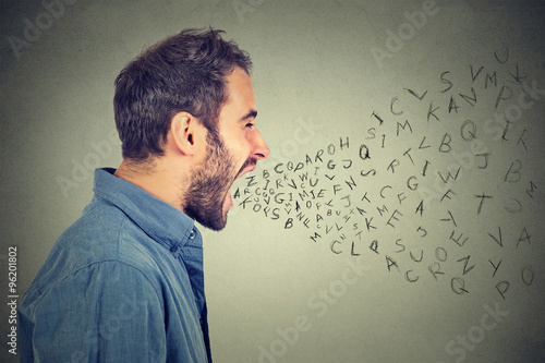 angry man screaming with alphabet letters flying out of wide open mouth photo