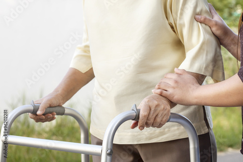 senior woman using a walker with caregiver © toa555