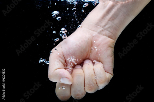 Male Clenched Fist with Bubbles of Air in the Water on Black Background. © iamdot