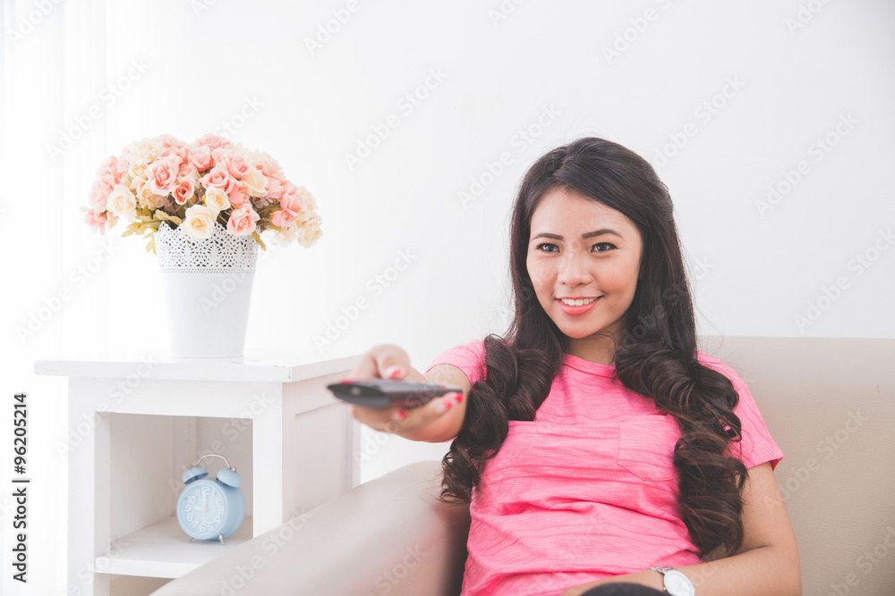 Woman sitting on a couch, using remote control Woman sitting on a couch, using remote control