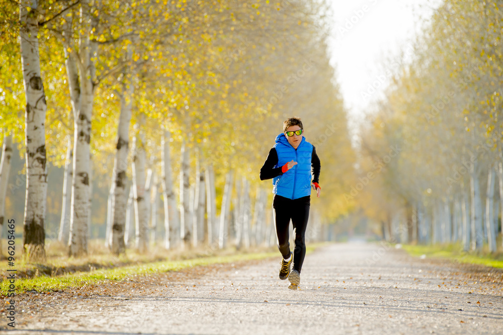 Obraz premium sport man running outdoors in off road trail ground with trees under beautiful Autumn sunlight
