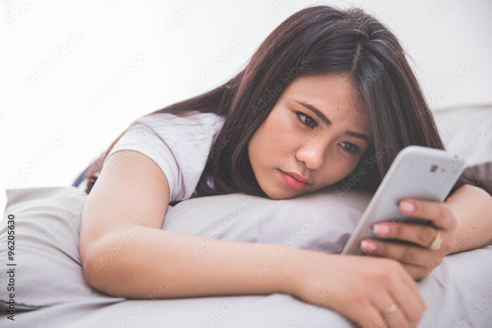 Woman using cellphone on the bed Woman using cellphone on the bed