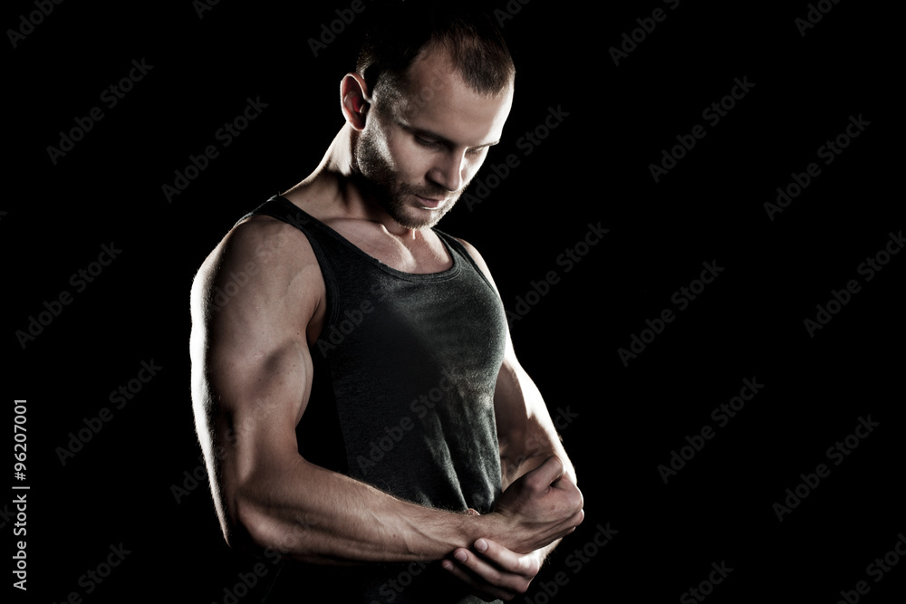 muscular man, clasps hands in fist, black background, place for text on the right muscular man, clasps hands in fist, black background, place for text on the right