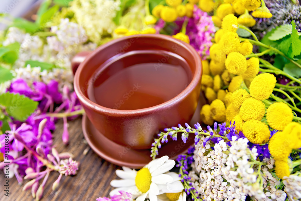 Tea from wild flowers in clay cup on board Tea from wild flowers in clay cup on board