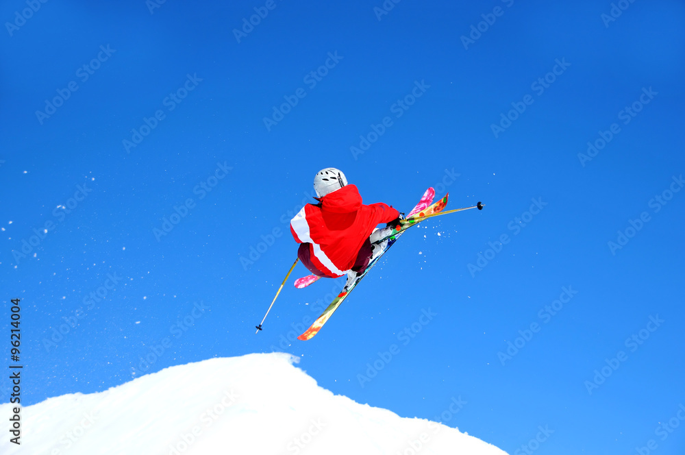 skier in red taking off on a jump