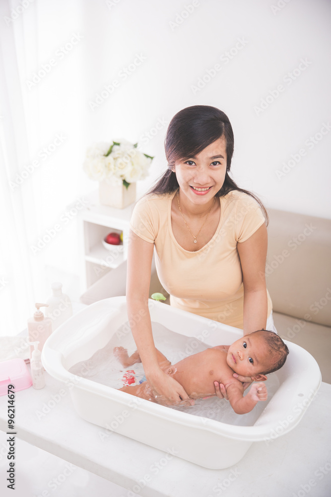 baby is being bathed by his mother
