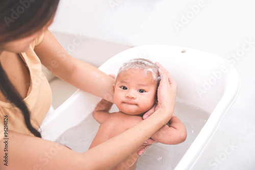 baby is being bathed and shampooed by his mother