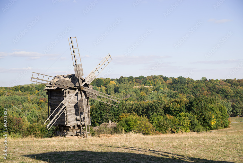 Fototapeta premium Windmill standing on the edge of the autumn forest