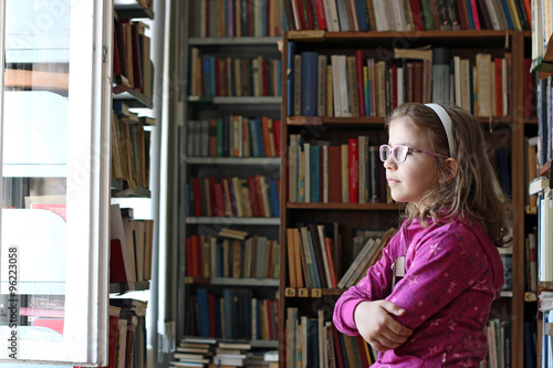 little girl with book in library