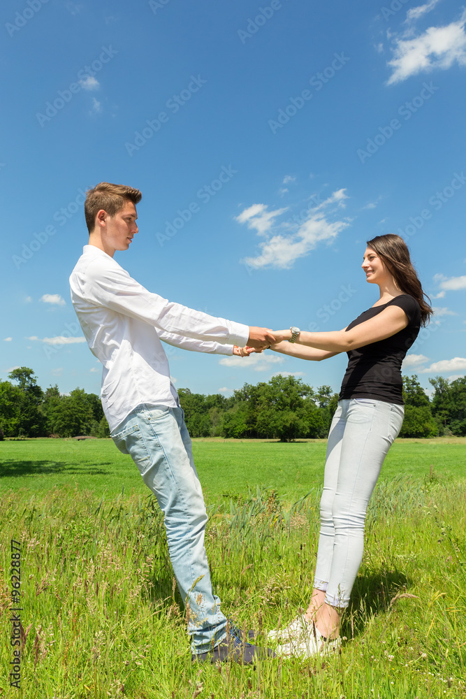 Young attractive couple holding each other in sunny meadow Young attractive couple holding each other in sunny meadow