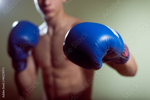 Male training box punches with bandages closeup on strong muscles of torso over dark background. Boxing workout © gorosi