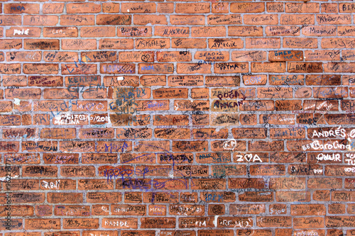 Random names written on brick wall. photo