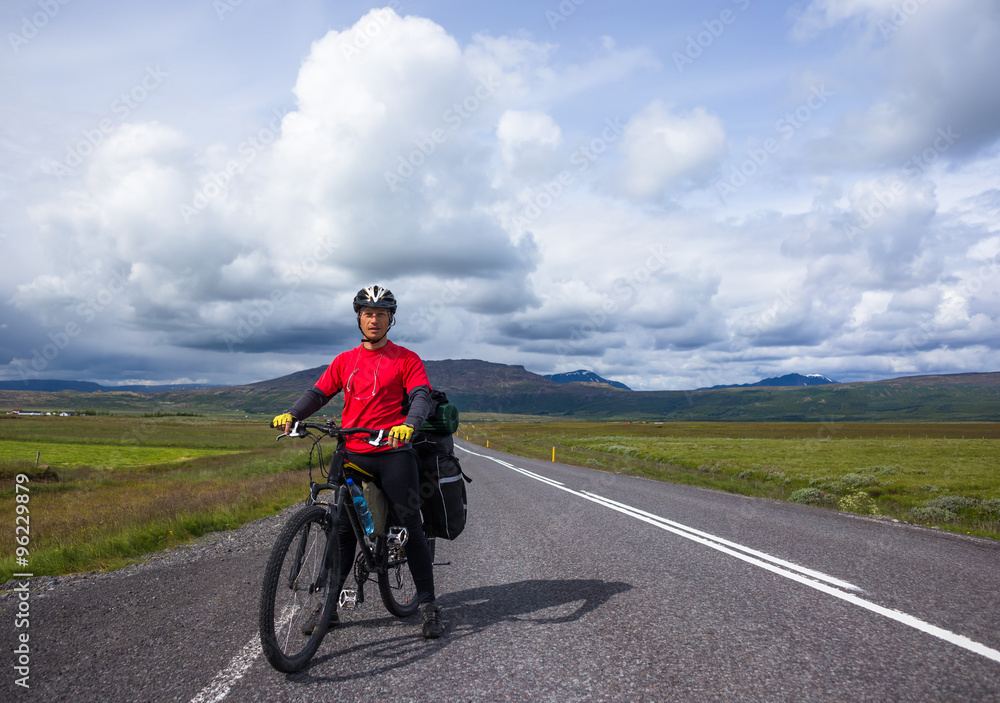 Biker rides on road at sunny summer day in Iceland Biker rides on road at sunny summer day in Iceland