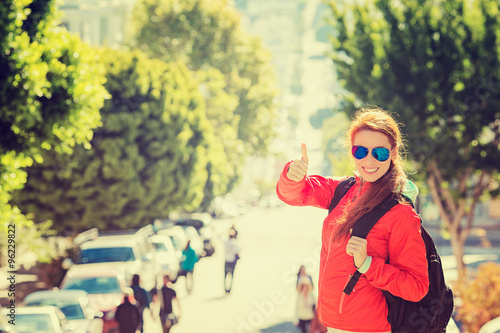 smiling woman with sunglasses and backpack in San Francisco city on sunny day © pathdoc