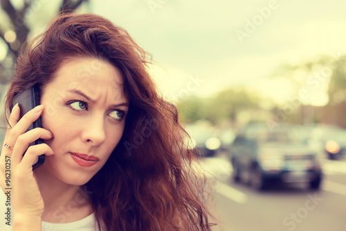 unhappy angry young woman talking on mobile phone looking frustrated