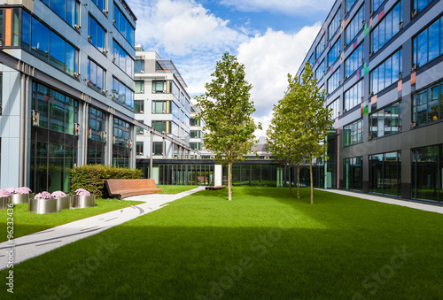 Modern office park with green lawn, trees and bench photo