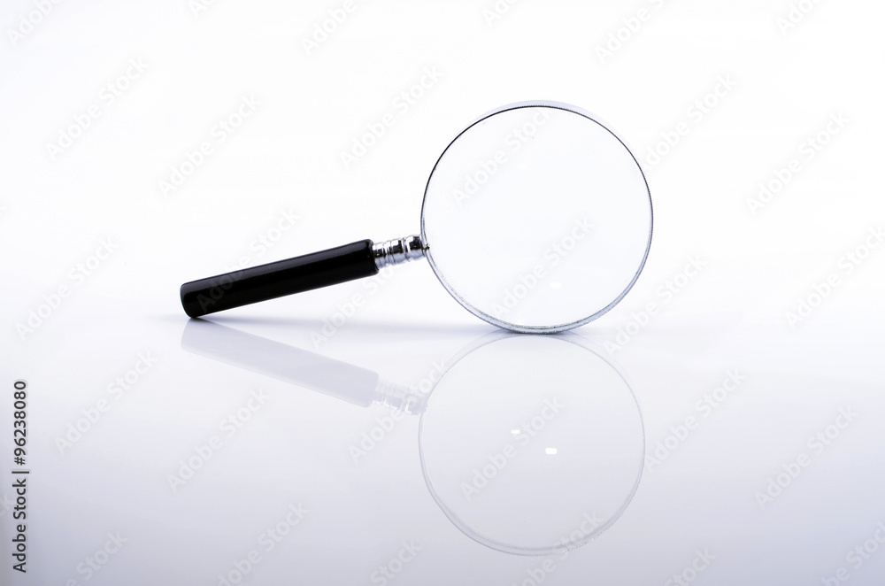 Magnifying glass in a metal frame with rubber black handle on w Magnifying glass in a metal frame with rubber black handle on w